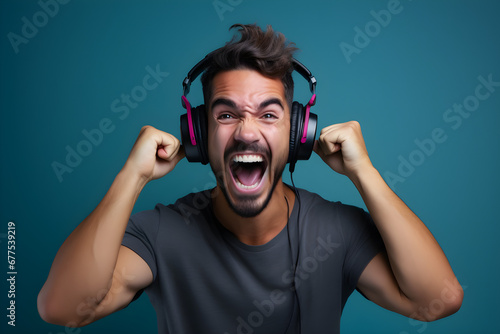 studio portrait of happy gamer man wearing headphones celebrating on blue background
 photo