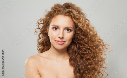 Cute woman with wavy hair and natural makeup. Young fashion model with long curly hairstyle and fresh clear skin posing on white background