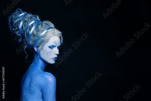 Fantastic cool cold woman with blue and white body art, carnival makeup and hairstyle on black background