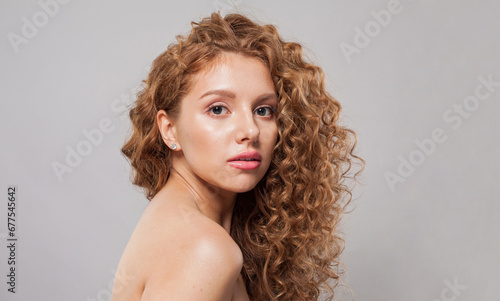 Attractive woman with wavy hair and natural makeup. Young fashion model with long curly hairstyle and fresh clear skin posing on white background