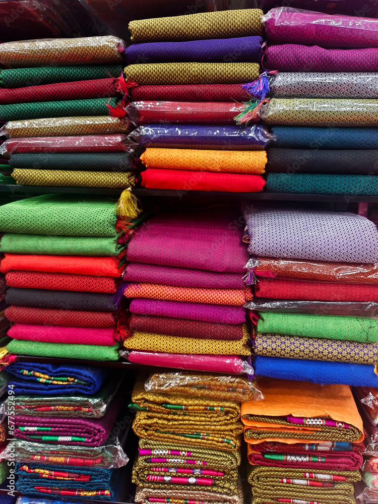 Neatly stacked colorful silk saris in racks in a textile shop, These exquisite, expensive sarees are famous for their gold and silver zari, brocade. Incredible India. Neatly stacked colorful silk saris in racks in a textile shop, These exquisite, expensive sarees are famous for their gold and silver zari, brocade. Incredible India.