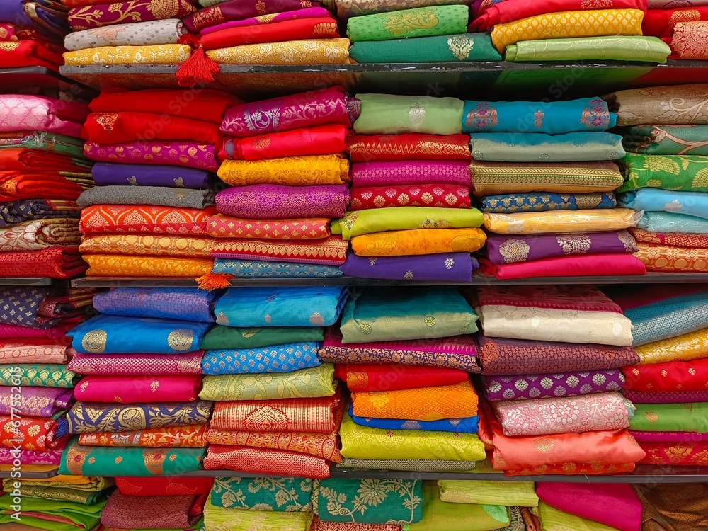 Neatly stacked colorful silk saris in racks in a textile shop, These exquisite, expensive sarees are famous for their gold and silver zari, brocade. Incredible India. Neatly stacked colorful silk saris in racks in a textile shop, These exquisite, expensive sarees are famous for their gold and silver zari, brocade. Incredible India.