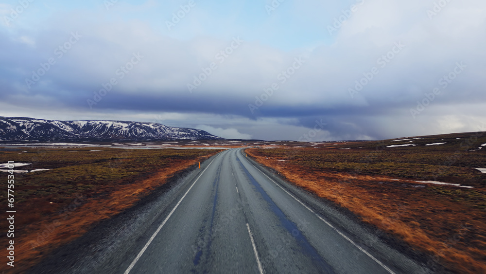 Large roads and snowy mountain tops with frozen green fields in iceland, aerial view of nordic roadside with spectacular scenery. Scandinavian nature and icelandic landscapes.