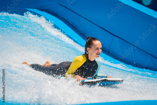 Beautiful young woman surfing on a wave simulator at a water amusement park © romaset