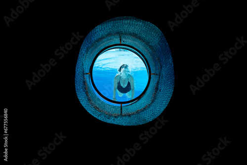 Woman Swimming in the Ship Porthole in Underwater in Swimming Pool in a Sunny Day in Switzerland.