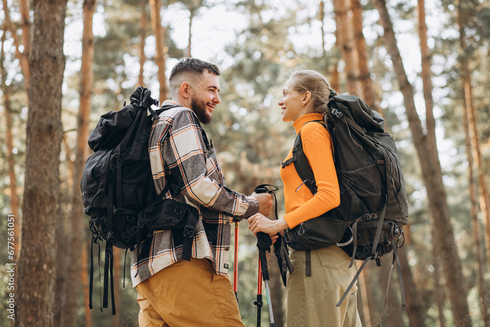 Couple hiking with bags and walking sticks in forest Couple hiking with bags and walking sticks in forest