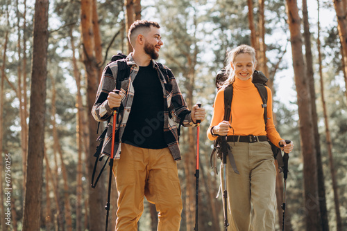 Couple hiking with bags and walking sticks in forest © Petro
