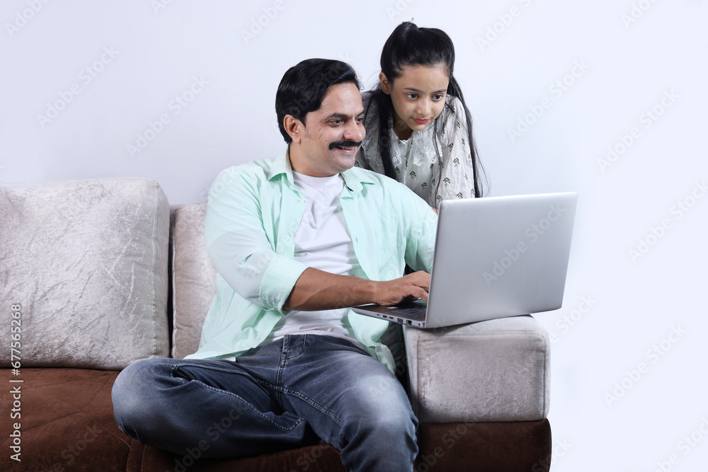 Happy Indian family of single father and daughter surfing laptop having pleasant time together joyfully. Family is looking into the laptop. Happy Indian family of single father and daughter surfing laptop having pleasant time together joyfully. Family is looking into the laptop.