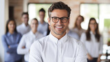 Portrait of happy young businessman in eyeglasses looking at camera with colleagues in background