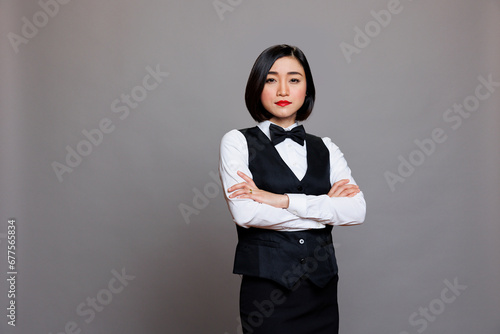 Professional asian woman waitress standing with arms crossed portrait. Serious receptionist in uniform showing confidence while posing with folded hands and looking at camera