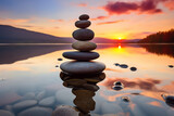 A delicate stack of balanced stones stands on the shore of a tranquil lake, the soft hues of the setting sun reflecting off the water's surface