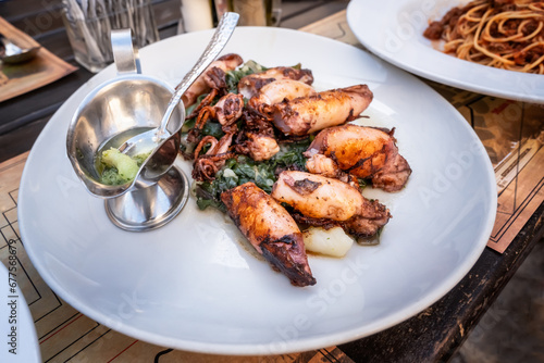 Foto Grilled baby squids on a plate with mashed potatoes and spinach garnish served in a traditional seafood restaurant in Montenegro