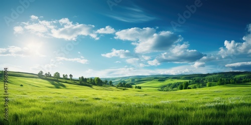 Beautiful panoramic landscape of a green field with grass against a blue sky with sun. Spring summer nature background.
