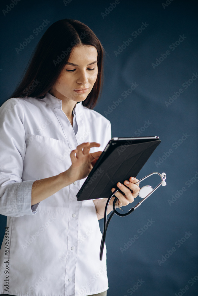 Young woman doctor in lab coat holding tablet and checking analyses Young woman doctor in lab coat holding tablet and checking analyses