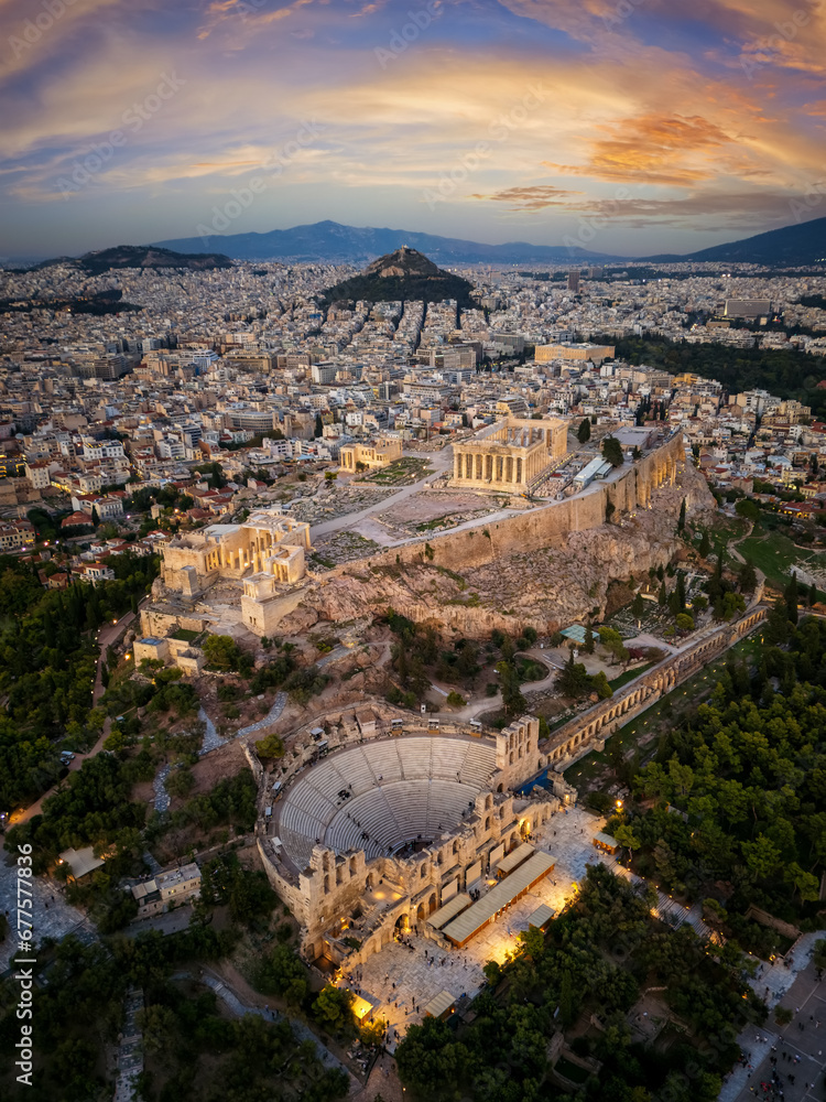 Aerial view of the skyline and ancient ruins at the Acropolis of Athens, Greece, and Odeon of Herode theatre during sunset time