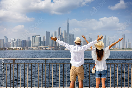 A happy tourist couple on a sightseeing tour enjoys the panoramic view of the skyline of Dubai, UAE photo