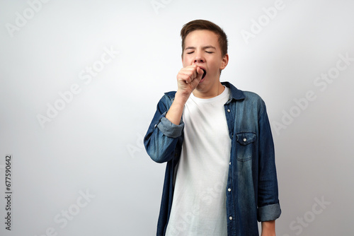 Tired school boy, yawning covering open mouth with hand photo