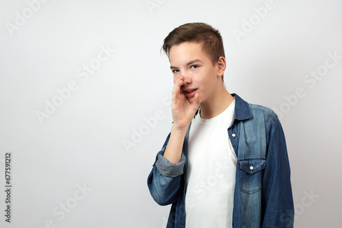 Teenage boy holding hand near mouth and telling secret