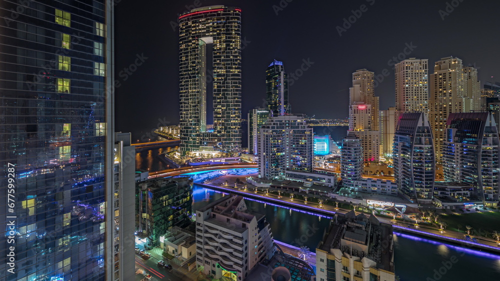 Obraz premium Panorama showing Dubai Marina with several boat and yachts parked in harbor and skyscrapers around canal aerial night timelapse.