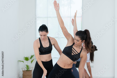 Fototapeta Naklejka Na Ścianę i Meble -  Yoga instructor assisting pupils in doing yoga poses in the studio, Yoga class concept