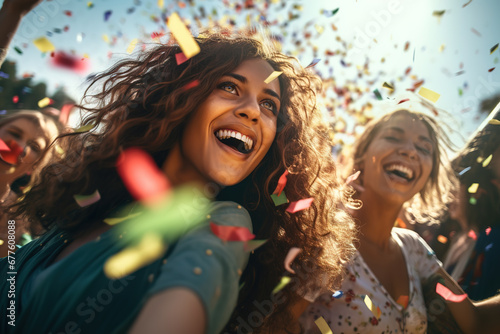 Friends having fun throwing confetti at party outdoor at open air avenue. Young trendy people enjoying fest event. Hangout, friendship, trends and youth concept