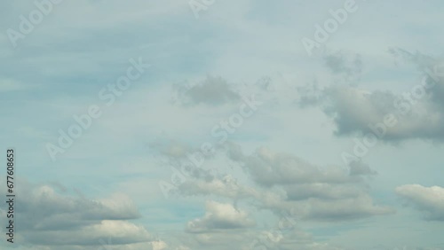 Time lapse of many clouds floating in the breeze in a clear daytime sky.