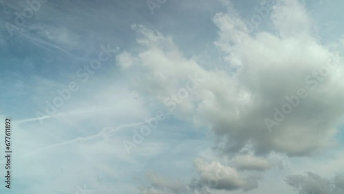 Time lapse of many clouds floating in the breeze in a clear daytime sky.