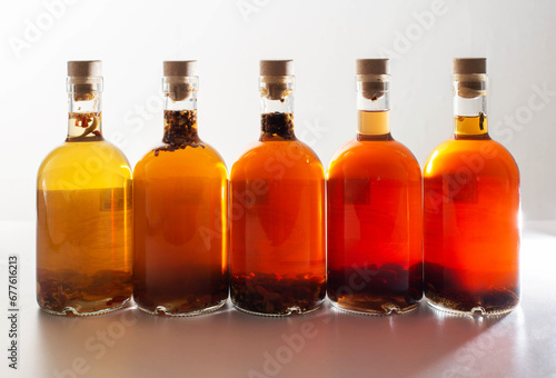 Transparent bottles with brown alcoholic drink on a white background. The concept of homemade herbal tinctures from moonshine. Homemade cognac and brandy.