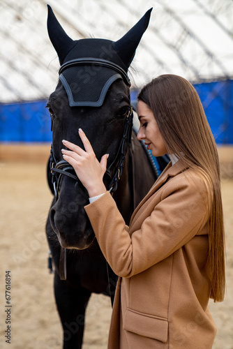 A Graceful Woman and Her Majestic CompanionA woman standing next to a black horse.