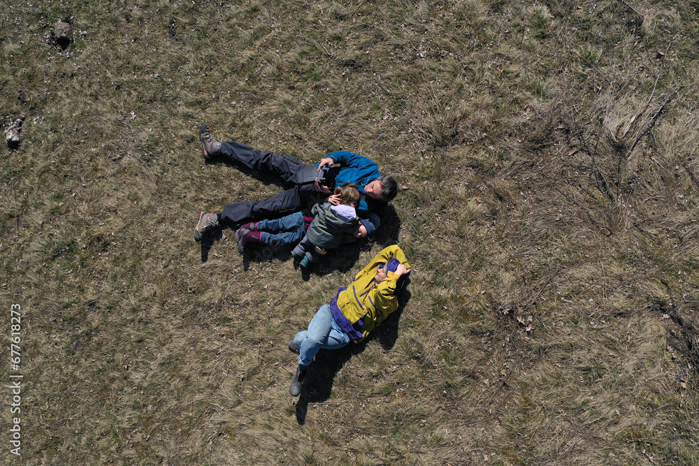 Obraz premium Aerial view of a happy family with, mom, dad and two kids laying in the grass