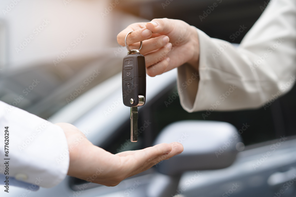 transportation rental automotive business concept. Close up hands of rental auto agent giving car remote key to client to travel sightseeing.