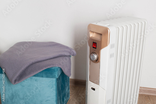 Electric heater on a white background next to a warm blanket. The concept of fire safety during the cold period when using an electric heater. Copy space for text, industry photo