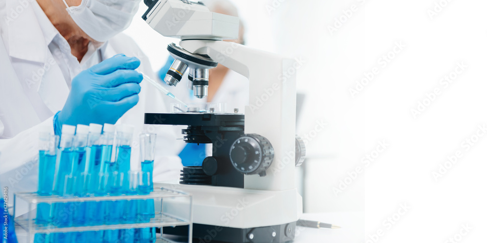 Fototapeta premium scientists conducting research investigations in a medical laboratory, a researcher in the foreground is using a microscope in laboratory for medicine. ..