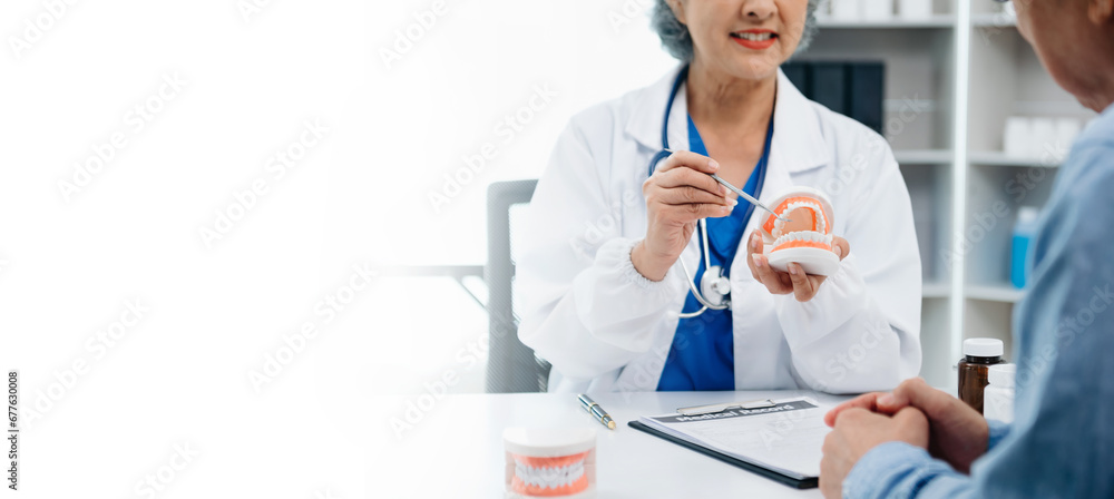 Concentrated dentist sitting at table with jaw samples tooth model and working with tablet and laptop in dental office professional dental clinic. medical doctor working .. Concentrated dentist sitting at table with jaw samples tooth model and working with tablet and laptop in dental office professional dental clinic. medical doctor working ..
