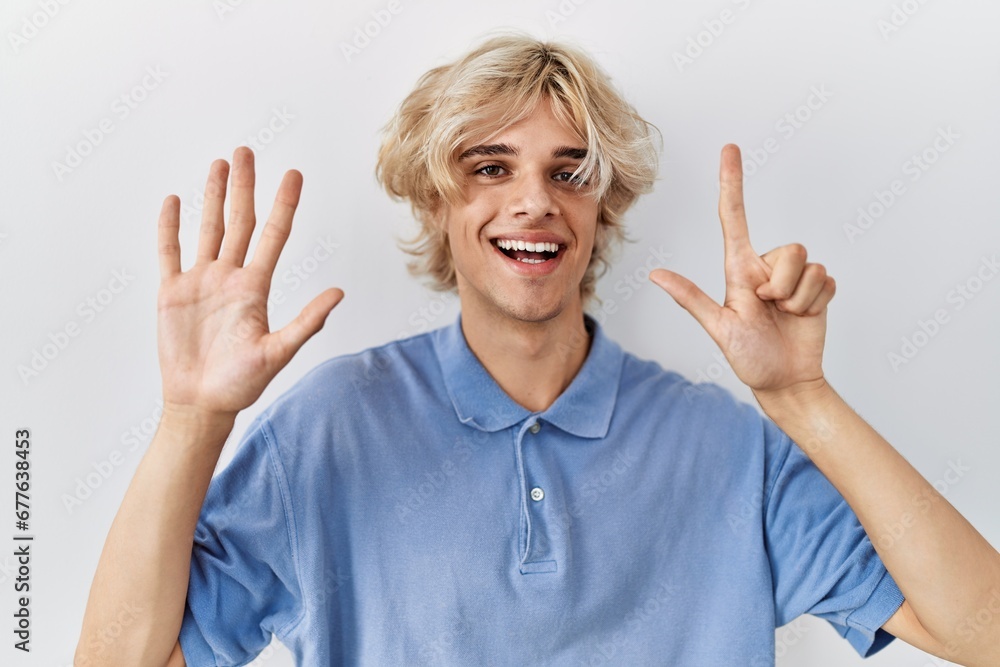 Young modern man standing over isolated background showing and pointing up with fingers number seven while smiling confident and happy. Young modern man standing over isolated background showing and pointing up with fingers number seven while smiling confident and happy.