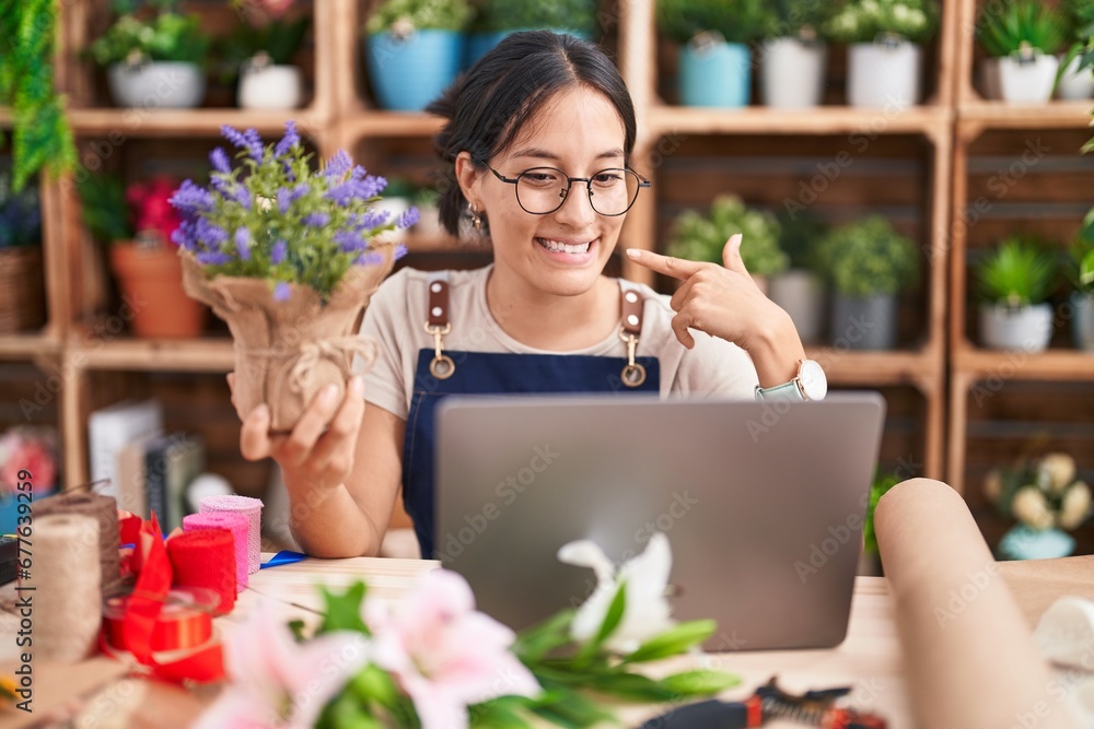 Young hispanic woman working at florist shop doing video call smiling cheerful showing and pointing with fingers teeth and mouth. dental health concept. Young hispanic woman working at florist shop doing video call smiling cheerful showing and pointing with fingers teeth and mouth. dental health concept.