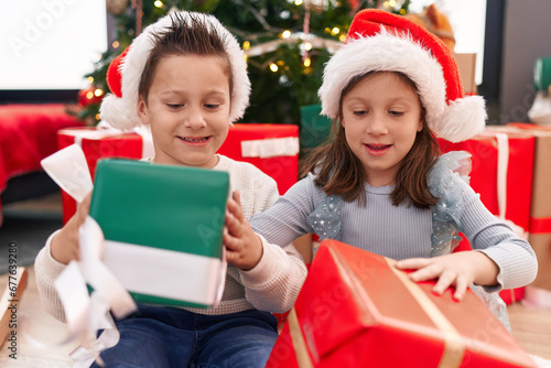 Adorable boy and girl smiling confident holding christmas gift at home