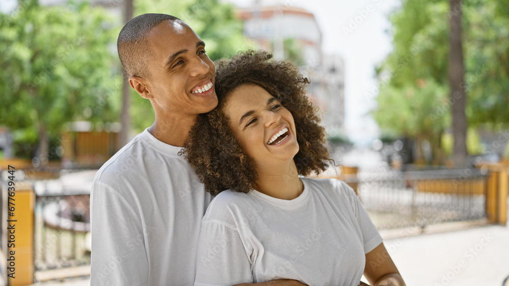 Beautiful couple, brimming with joy and laughter, standing confidently, hugging, and looking up at the sky in the park with smiles. Beautiful couple, brimming with joy and laughter, standing confidently, hugging, and looking up at the sky in the park with smiles.