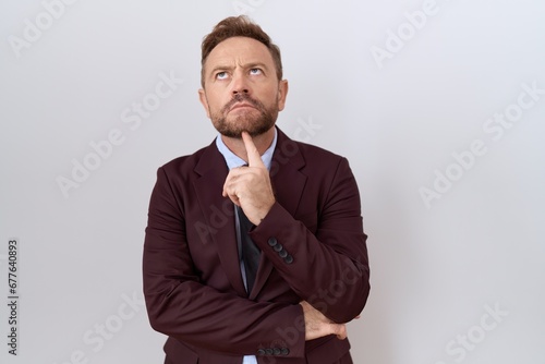 Middle age business man with beard wearing suit and tie thinking concentrated about doubt with finger on chin and looking up wondering