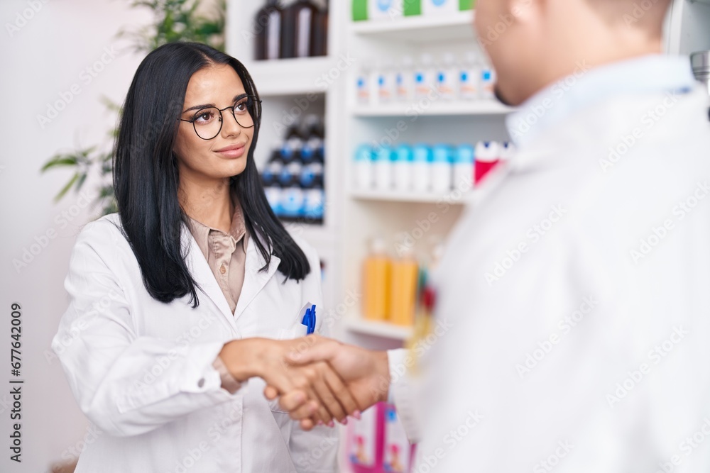 Man and woman pharmacists smiling confident shake hands at pharmacy Man and woman pharmacists smiling confident shake hands at pharmacy