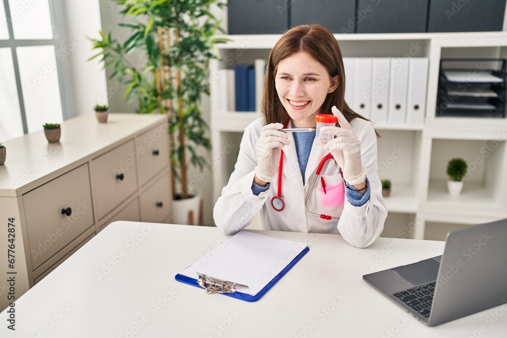 Young blonde woman doctor pointing to empty test tube speaking at clinic Young blonde woman doctor pointing to empty test tube speaking at clinic