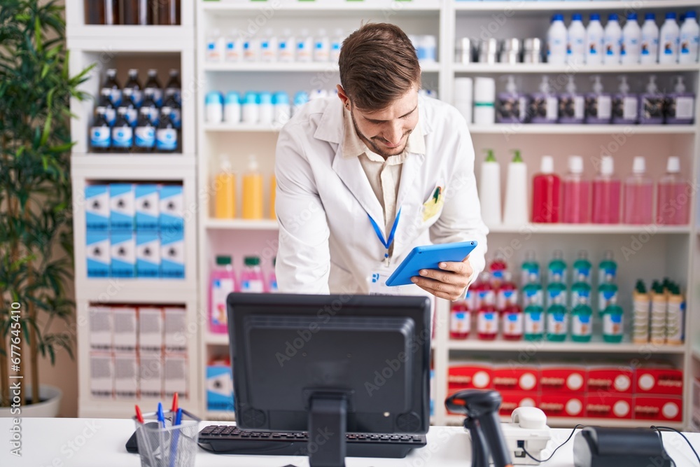 Young caucasian man pharmacist using computer and touchpad at pharmacy Young caucasian man pharmacist using computer and touchpad at pharmacy