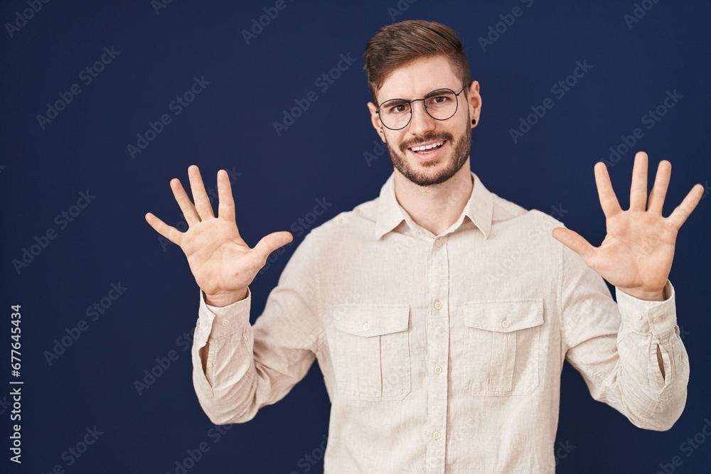 Hispanic man with beard standing over blue background showing and pointing up with fingers number ten while smiling confident and happy. Hispanic man with beard standing over blue background showing and pointing up with fingers number ten while smiling confident and happy.