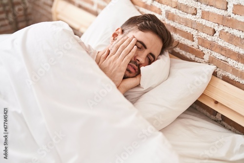 Young caucasian man stressed lying on bed at bedroom