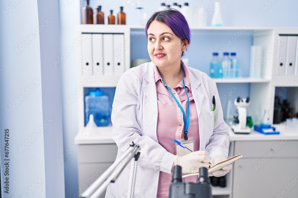 Young beautiful plus size woman scientist writing on notebook at laboratory Young beautiful plus size woman scientist writing on notebook at laboratory