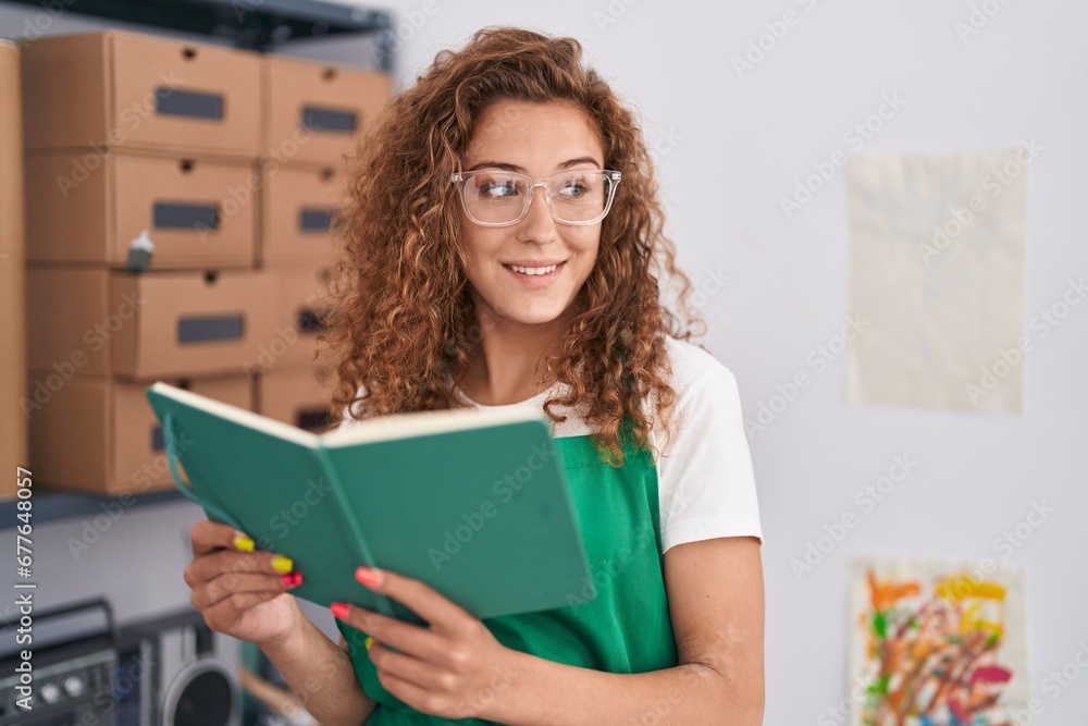 Young beautiful hispanic woman artist smiling confident reading book at art studio Young beautiful hispanic woman artist smiling confident reading book at art studio