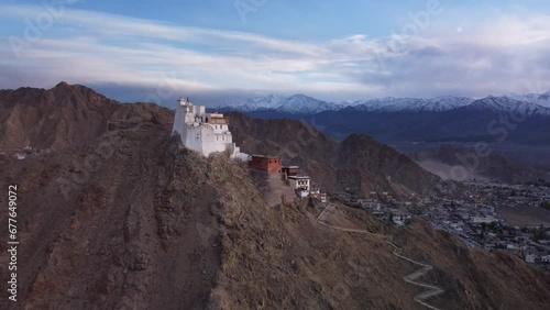 Cinematic drone shot revealing Sankar Monastery and temple overlooking the city of Leh with the view of snowcapped Himalayan mountain range in the background during sunset, Ladakh, India photo
