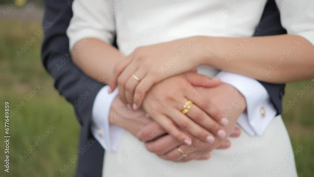 Newlywed Bride and groom hug as their hand touches each other with their wedding rings - The couple's hands caress each other. Newlywed Bride and groom hug as their hand touches each other with their wedding rings - The couple's hands caress each other.