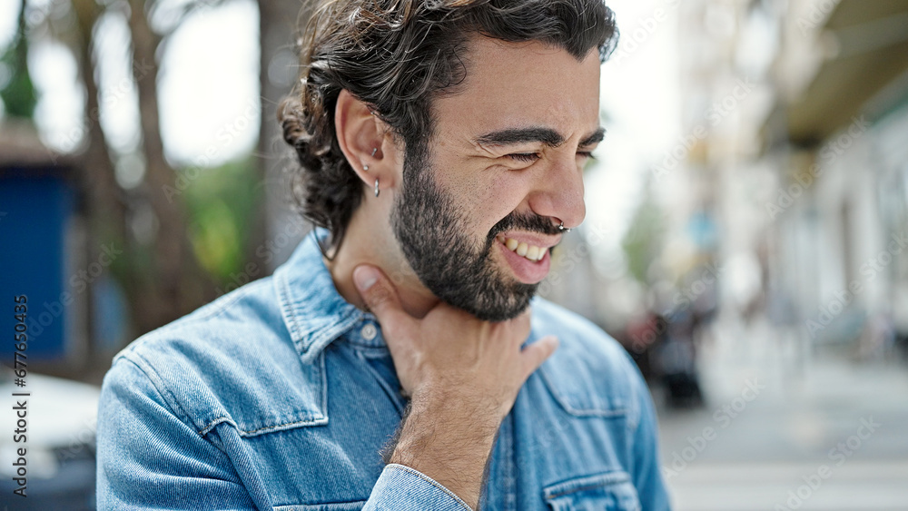 Fototapeta premium Young hispanic man suffering for throat pain at street