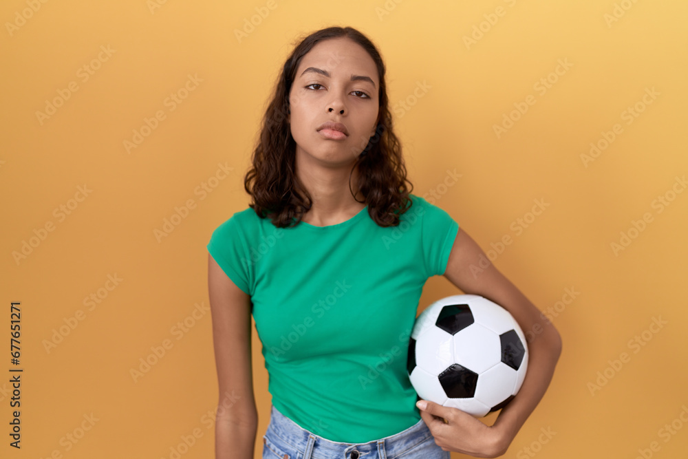 Young hispanic woman holding ball looking sleepy and tired, exhausted for fatigue and hangover, lazy eyes in the morning.